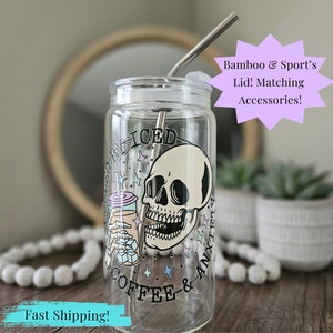May include: A clear glass tumbler with a skull graphic and the text "Iced Coffee & Anxiety" printed on it. The tumbler has a lid and a stainless steel straw.