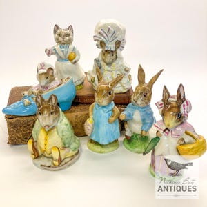 May include: A collection of ceramic figurines featuring anthropomorphic animals. The figurines include a cat, mice, and rabbits dressed in detailed clothing. The figurines are in various poses, some holding baskets or other items. The color palette includes pastels and earth tones.
