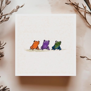 Carte de souhaits avec trois grenouilles colorées, illustration minimaliste amusante, idéale pour carte d’amitié ou occasion joyeuse!