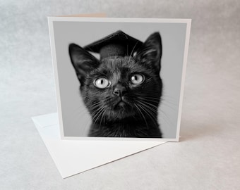 Puede incluir: Tarjeta de graduación en blanco y negro con un gato negro con birrete. El gato tiene ojos grandes y bigotes. La tarjeta está sobre un sobre blanco.