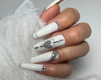 Bruiloft nagels. Witte press-on nagelgeltips met strass-steentjes en zilveren versieringen