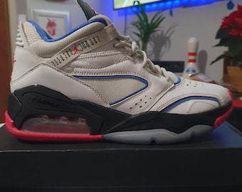 May include: White, black, and blue sneakers with a pink and black sole. The sneakers have a blue and white stripe on the side and the text "133052-100 002" on the side.