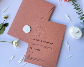 May include: A peach-colored save the date card with the text "Save the Date" in black lettering. The card also includes the names "Helin & Ferhat" and the date "14.10.2023".