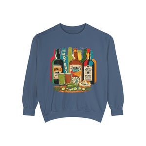 May include: A blue sweatshirt featuring a vintage-style graphic of six bottles of liquor and a plate of pickles. The bottles are labelled "Pickles", "The Notery", "Pickles", "Pickles", "F.C.K.I.O", and "Firenze".