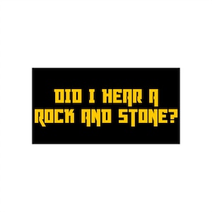 Op de afbeelding: Een zwarte rechthoek met de gele tekst "DID I HEAR A ROCK AND STONE?" in een pixelachtige lettertype. De tekst is gecentreerd. De achtergrond is wit.