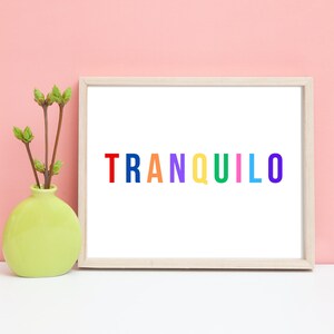May include: A framed print with the word "TRANQUILO" spelled out in rainbow colours. The print is on a white background and is framed in a light wood frame.