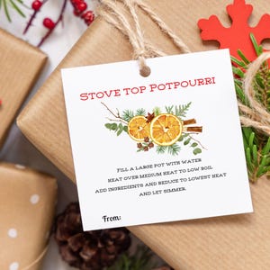 May include: A white gift tag with the words "STOVE TOP POTPOURRI" in red. The tag features a watercolour illustration of dried orange slices, cinnamon sticks, and greenery. Instructions are printed below the illustration.