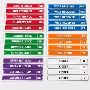 Puede incluir: Una colección de etiquetas adhesivas rectangulares para tableros de draft de fútbol americano. El set incluye etiquetas rojas para Quarterback, azules para Wide Receiver, verdes para Running Back, naranjas para Tight End, moradas para Defense/Team y blancas para Kicker.