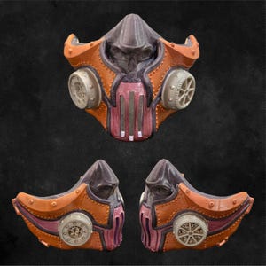 May include: A steampunk-style mask in shades of orange, purple, and gray. The mask features a detailed design with rivets, vents, and circular side elements. The overall aesthetic suggests a post-apocalyptic or industrial theme.
