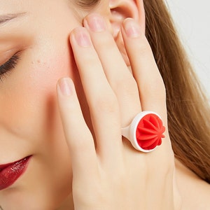 May include: A white ring with a red, star-shaped design. The ring is made of a smooth, plastic-like material.