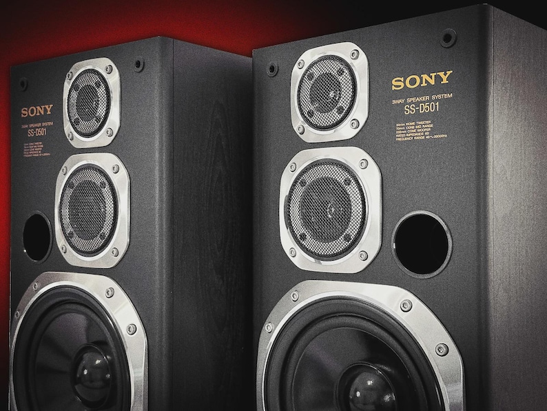 Puede incluir: Dos sistemas de altavoces Sony SS-D501 de 3 v&iacute;as de color negro. Cada altavoz tiene un woofer circular grande, dos altavoces de rango medio m&aacute;s peque&ntilde;os y un tweeter. Los altavoces tienen detalles plateados y el logotipo de Sony en dorado. El texto "3 WAY SPEAKER SYSTEM" es visible.