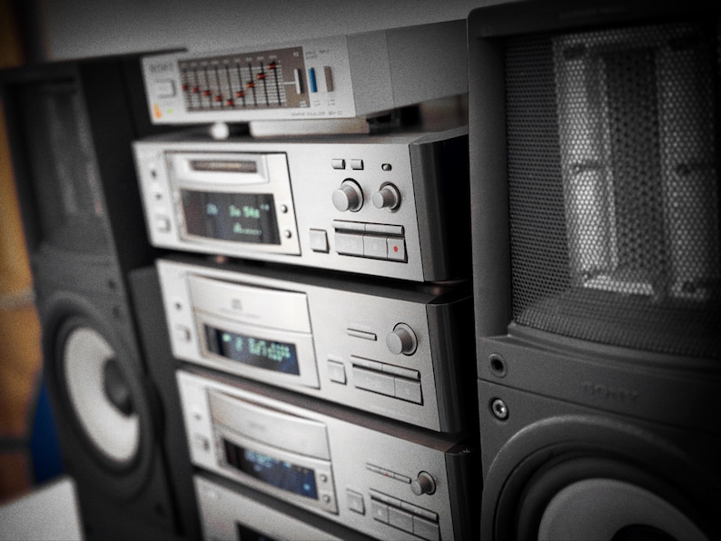 Puede incluir: Una pila de componentes de audio plateados vintage, que incluyen un reproductor de CD, una pletina de casete y un amplificador, con un ecualizador gr&aacute;fico en la parte superior. Un gran altavoz negro est&aacute; a la derecha. Los componentes tienen botones y pantallas.
