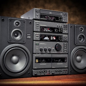 以下が含まれることがあります： 黒色のヴィンテージソニー製ステレオシステム。2つの大きなスピーカーと、CDプレーヤー、チューナー、カセットデッキなどの複数のコンポーネントで構成されています。システムにはさまざまなボタンとディスプレイがあります。スピーカーは長方形です。