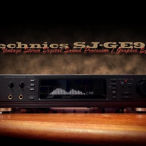 May include: A black Technics SJ-GE90 vintage stereo digital sound processor and graphic equaliser. The unit has a display showing a graphic equaliser, with knobs and buttons. It sits on a wooden surface.