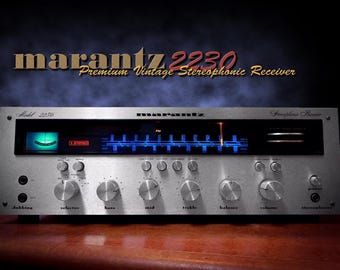May include: A silver Marantz 2230 stereo receiver with multiple knobs and a blue and green illuminated display. The text "marantz 2230 Premium Vintage Stereophonic Receiver" is above the receiver. The receiver is on a brown surface.
