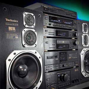 May include: A black Technics stereo system with speakers and multiple components. The speakers have large, round woofers and smaller tweeters. The components include a CD player, cassette deck, and amplifier. The system is set against a dark background.