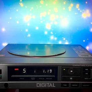 May include: A silver and black Sony CDP-7F compact disc player. The display shows "5 1 1.19". The unit has a disc tray, power button, and control buttons. The word "DIGITAL" is printed on the front.