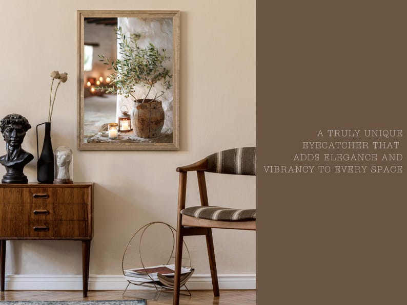 May include: A framed print of a still life featuring a potted olive branch, candles, and a rustic wooden bowl. The print is in a light wood frame and is hanging on a beige wall.