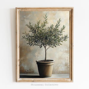 May include: A framed painting of a potted olive tree with green leaves against a textured beige background. The painting is in a light wood frame.