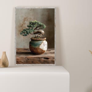 May include: A framed image of a bonsai tree in a ceramic pot. The bonsai has green foliage and a curved trunk. The pot is brown, white, and teal. The image is on a wooden surface.