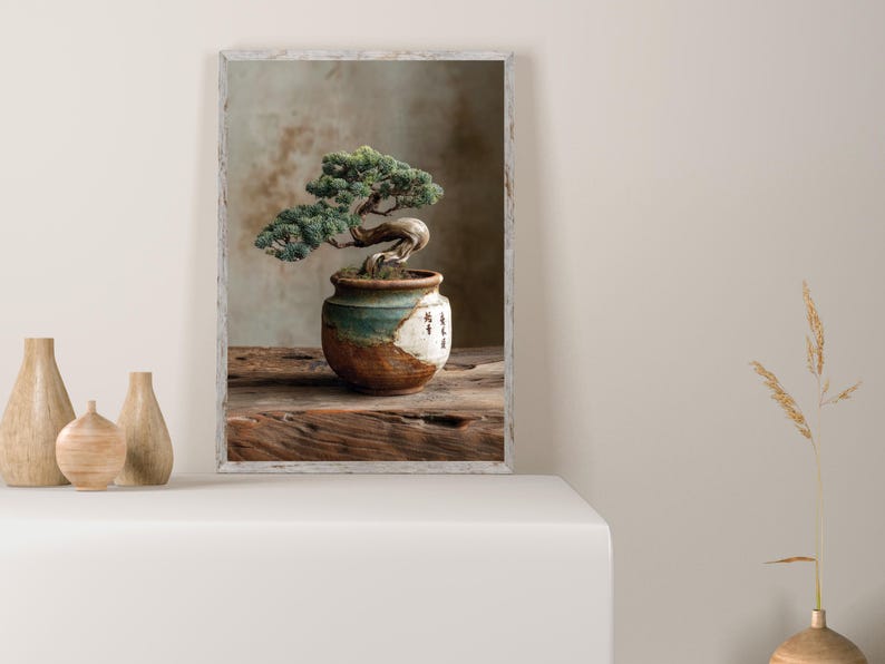 May include: A framed image of a bonsai tree in a ceramic pot. The bonsai has green foliage and a curved trunk. The pot is brown, white, and teal. The image is on a wooden surface.