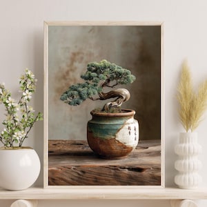 May include: A framed print of a bonsai tree in a ceramic pot. The tree has green foliage and a twisted trunk. The pot is brown and teal, with Japanese characters. The print is on a wooden surface.