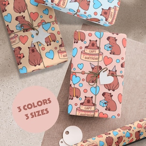 May include: Three different wrapping paper designs featuring capybaras wearing party hats and holding gifts. The designs are on a pink, light brown, and blue background. The text "Capy Birthday" is on the pink design. The text "3 Colors 3 Sizes" is on a pink circle.