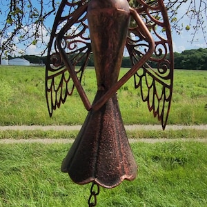 Pu&ograve; includere: Un carillon a vento in metallo color rame con ali intricate tagliate e un fondo a forma di campana. Il carillon &egrave; appeso a una catena.