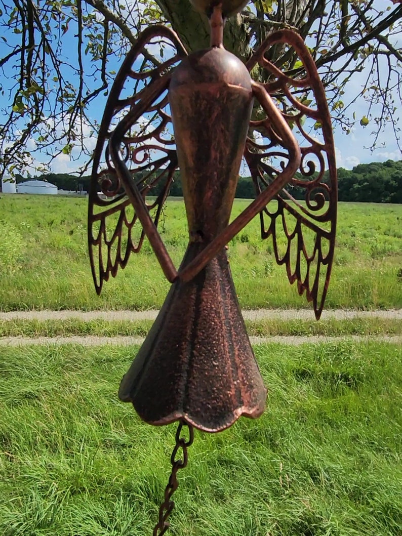 Pu&ograve; includere: Un carillon a vento in metallo color rame con ali intricate tagliate e un fondo a forma di campana. Il carillon &egrave; appeso a una catena.