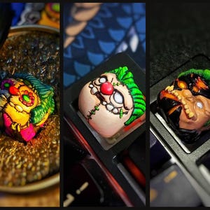 May include: Three custom-painted keycaps featuring different cartoon faces. The first keycap is green, yellow, and red with a clown face. The second keycap is green and white with a stitched-up monster face. The third keycap is black and green with a stitched-up monster face.
