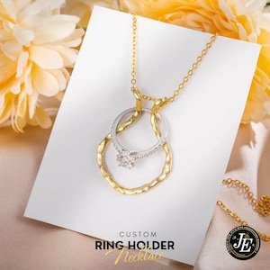 May include: A gold and silver ring holder necklace with a diamond ring. The necklace features a gold chain and two interlocking rings, one gold and one silver. The text "CUSTOM RING HOLDER Necklace" is at the bottom.