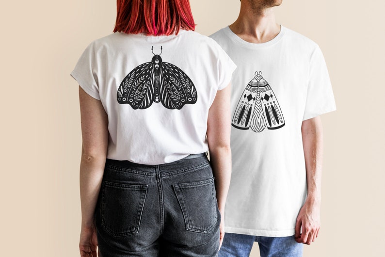 May include: Two white t-shirts with black and white moth designs. The moth on the left t-shirt has a more intricate design with floral elements. The moth on the right t-shirt has a more geometric design.