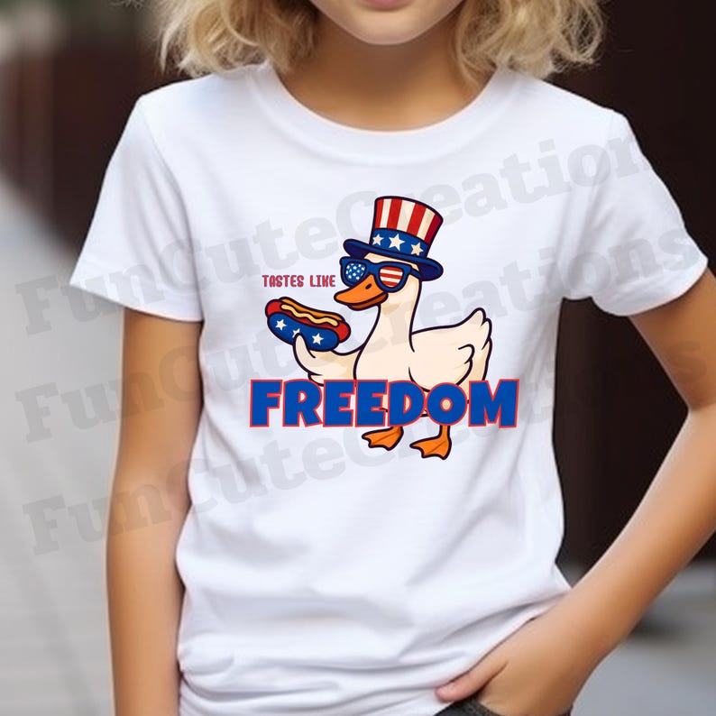 May include: White t-shirt featuring a cartoon duck wearing an Uncle Sam hat and sunglasses, holding a hot dog. The text "TASTES LIKE" is above the duck, and "FREEDOM" is below it, in red and blue.