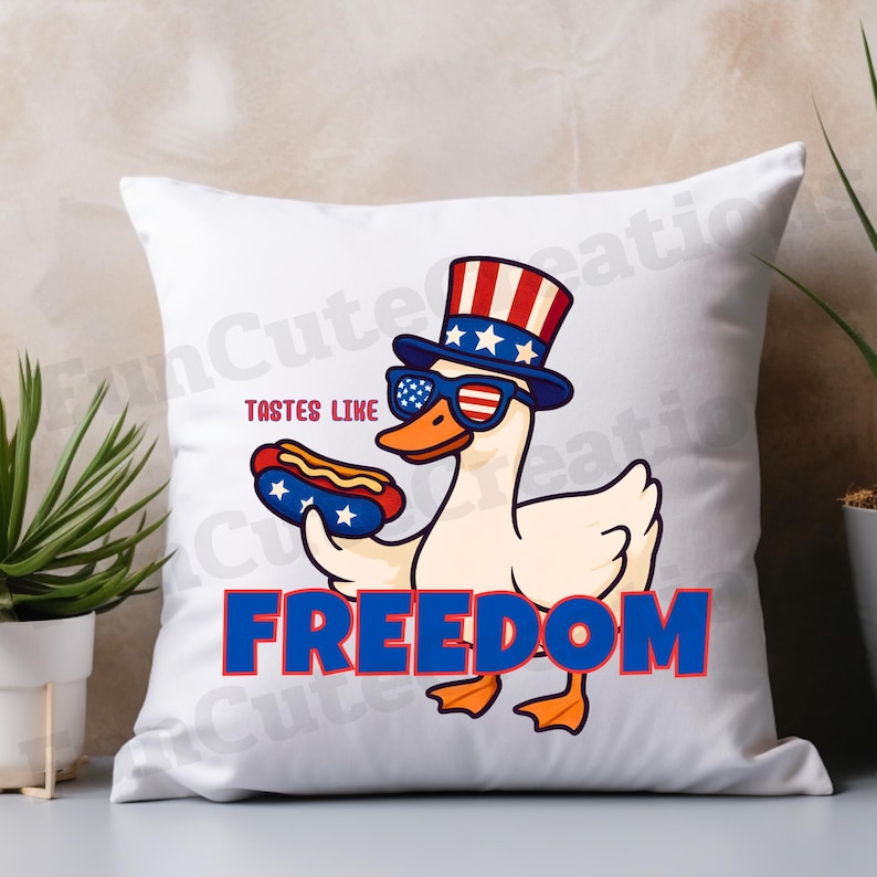 May include: White square pillow with a cartoon goose wearing sunglasses and a patriotic hat, holding a hot dog. The text "TASTES LIKE FREEDOM" is printed on the pillow in red and blue.