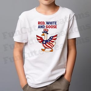 K&ouml;nnte beinhalten: Wei&szlig;es T-Shirt mit einem Cartoon-Gans-Design. Die Gans hat Fl&uuml;gel und einen Zylinder in Rot, Wei&szlig; und Blau. Der Text "RED, WHITE AND GOOSE" ist &uuml;ber der Gans aufgedruckt. Das Design integriert die amerikanische Flagge.