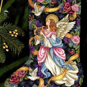 May include: A Christmas stocking featuring a gold ribbon and an angel playing a harp. The stocking is adorned with roses, doves, and snowflakes. The name Samantha is inscribed on the ribbon.