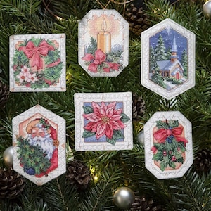 Puede incluir: Seis adornos navideños de punto de cruz que muestran una corona con lazo rojo, una vela encendida, una iglesia en la nieve, Santa Claus con un árbol, una flor de pascua roja y acebo con bayas, cada uno con un borde claro y texturizado.