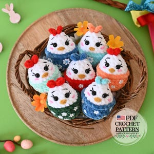 Könnte beinhalten: Eine Sammlung handgefertigter Häkelküken-Ornamente in einem Weidenkorb. Jedes Küken hat einen weißen Körper, ein farbenfrohes Outfit und eine Schleife. Die Küken sind mit schwarzen Augen und orangefarbenen Schnäbeln verziert. Der Korb steht auf einem Holztablett.