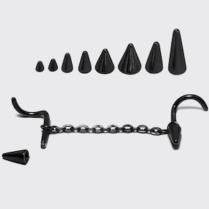 May include: A collection of black body jewelry, including a chain with curved ends and a series of cone-shaped plugs in varying sizes. The jewelry is displayed against a plain white background.