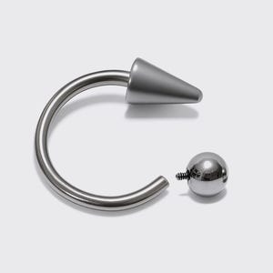 May include: A silver-colored body piercing jewelry piece. The jewelry features a curved barbell with a conical spike on one end and a small, round ball on the other. The piece is designed to be inserted into a piercing.