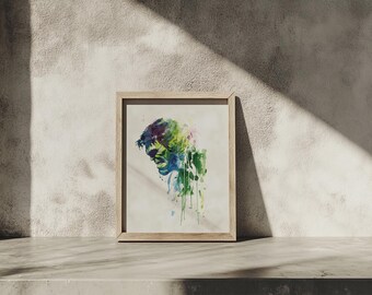 以下が含まれることがあります： 緑、青、紫の色合いで描かれた人物の横顔が特徴の、額装された水彩画プリント。 このアートワークは、木製の明るい色のフレームに入れられ、質感のあるニュートラルな色調の壁に飾られています。
