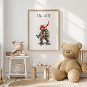 Op de afbeelding: Een ingelijst print met een aquarel-illustratie van een Teenage Mutant Ninja Turtle die een rode bandana draagt en een katana vasthoudt. De tekst "I AM BRAVE" is boven de illustratie gedrukt.