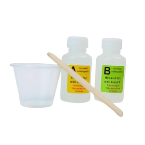 Könnte beinhalten: Zwei durchsichtige Plastikflaschen mit Etiketten, auf denen "nur zum Gießen" und "A und B gut vermischen" steht. Die Flaschen befinden sich neben einem kleinen durchsichtigen Plastikbecher und einem Holzrührstab.