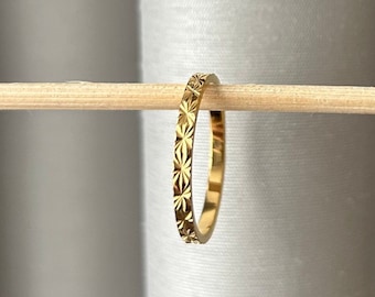 Peut inclure: Une fine bague en or avec un motif délicat en forme d'étoile autour de toute la bande.