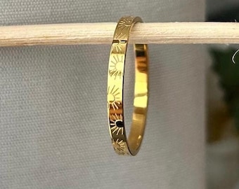 Peut inclure: Une fine bague en or avec un motif soleil gravé autour de toute la bande.