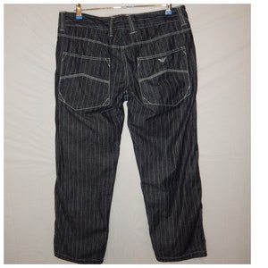 May include: Black and white striped pants with white stitching and a small logo on the back pocket.