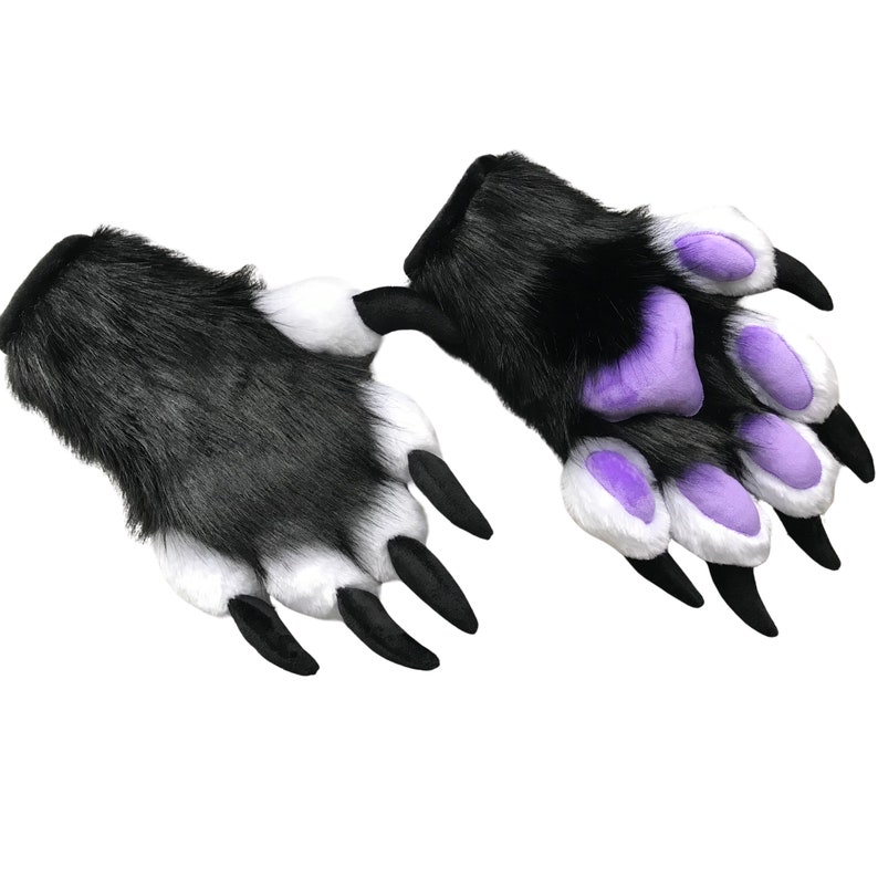 May include: A pair of furry paw gloves in black, white, and purple. The gloves have long black claws and are designed to resemble animal paws. The fur is black and white, with purple pads on the palms and fingers.
