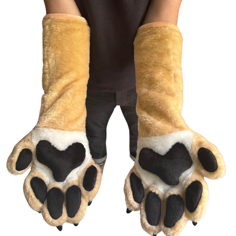 May include: A pair of plush, oversized paw gloves. The gloves are tan with white accents and large black paw pads. The gloves extend up the arm and are designed to resemble animal paws.
