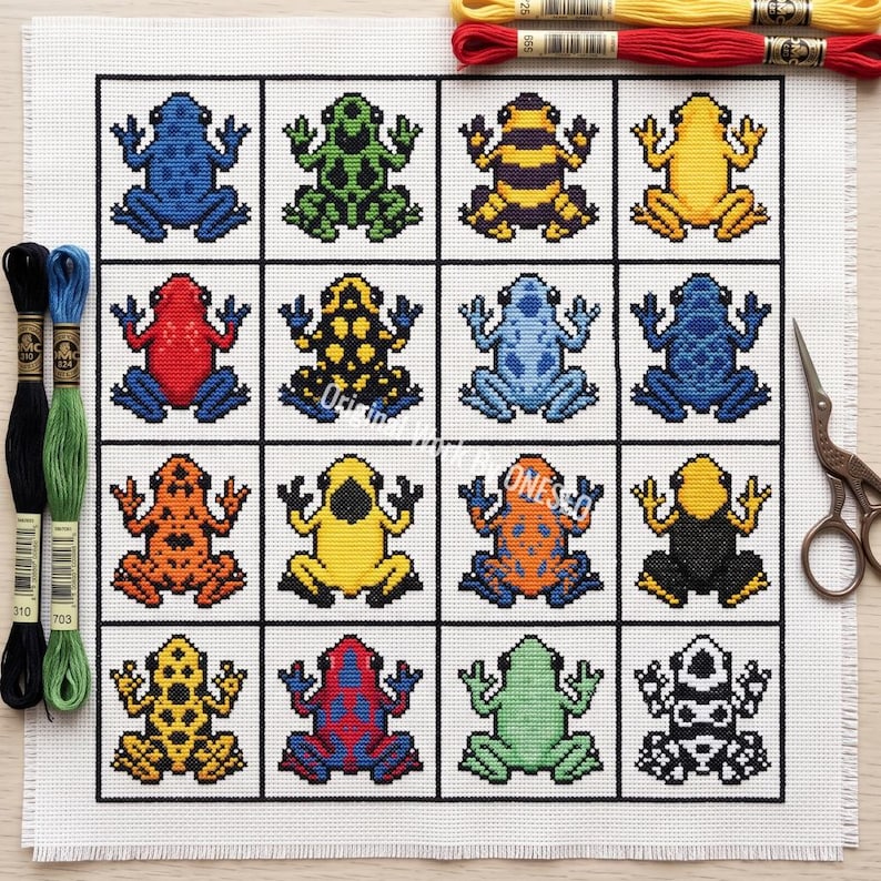 May include: A cross-stitch pattern on white fabric featuring a grid of sixteen colorful poison dart frogs in various patterns and colors, including blue, green, yellow, red, and orange, accompanied by embroidery floss and metal scissors.