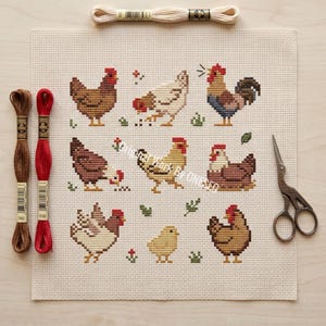 May include: A completed cross-stitch project featuring nine chickens and a chick in various poses, stitched on a cream-colored fabric. Embroidery floss in brown, red, and cream, along with small scissors, are arranged around the artwork. The design includes small floral and leaf accents.